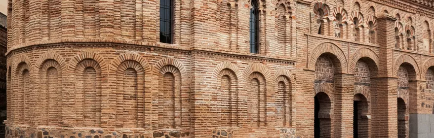 Fachada lateral de ladrillo con arcos ciegos y ventanas estrechas.