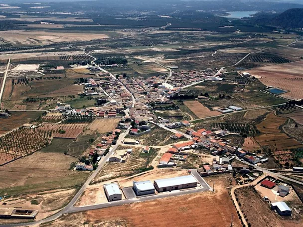 Vista aérea de un núcleo urbano rodeado de campos de cultivo y caminos rurales.