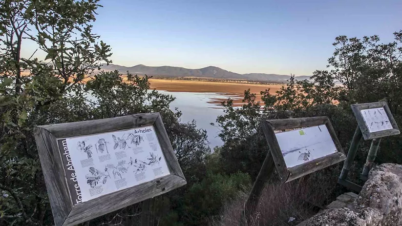 Mirador natural con paneles informativos y vistas a un gran embalse rodeado de montes.