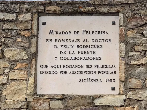 Placa conmemorativa en muro de piedra con arco inferior.