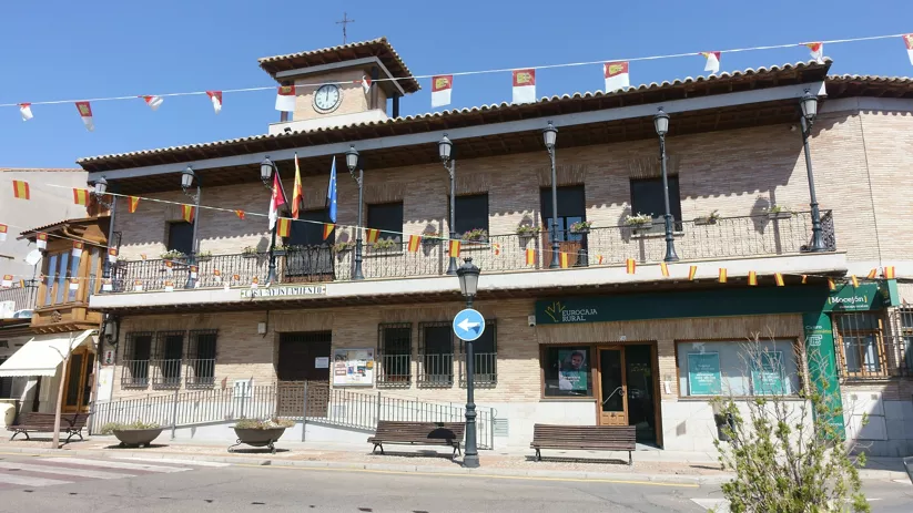 Fachada de ayuntamiento de ladrillo con balcones y banderines festivos