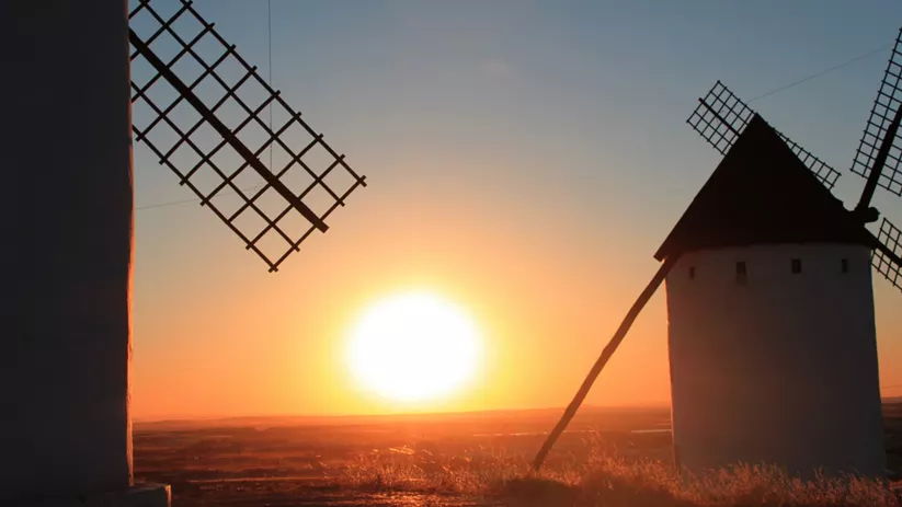 Molinos de viento al atardecer con el sol en el horizonte.
