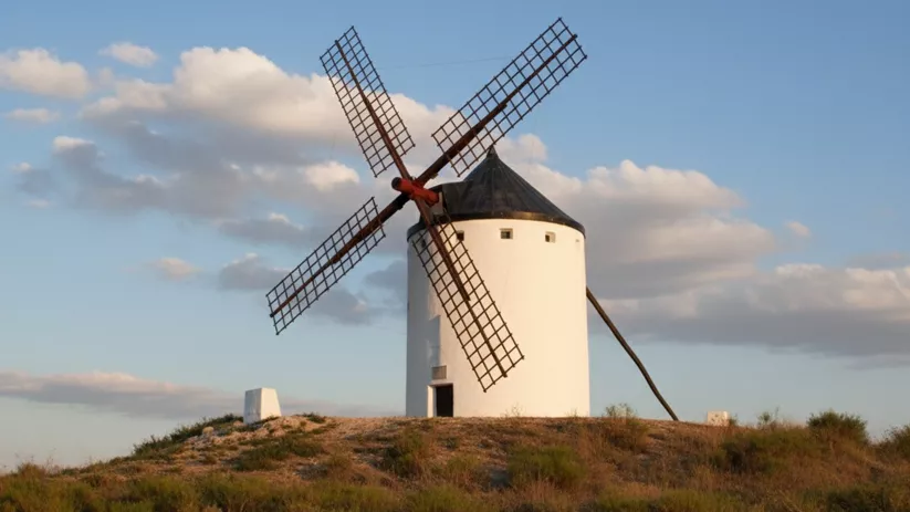 Molino solitario en colina baja rodeado de vegetación seca.