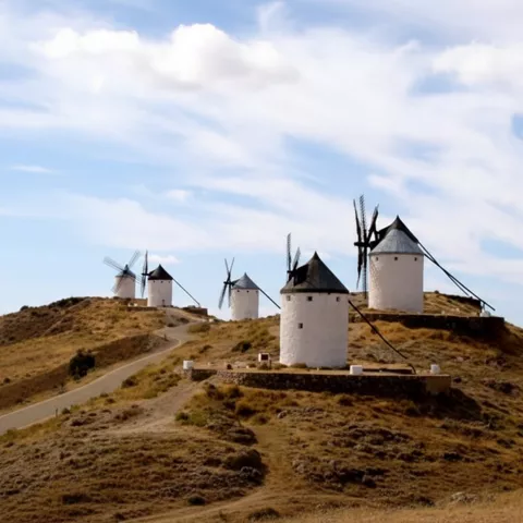 Conjunto de molinos tradicionales en loma seca bajo cielo nublado.