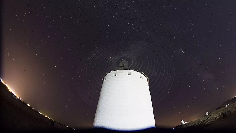 Molino de viento visto desde abajo bajo un cielo estrellado.