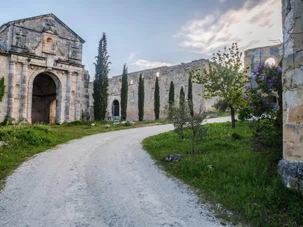 Portada monumental de piedra junto a camino rural.