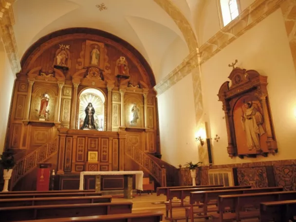 Interior de iglesia con bancos de madera y retablo tallado en madera al fondo.