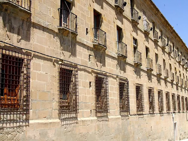 Fachada de piedra con balcones y rejas en ventanas.