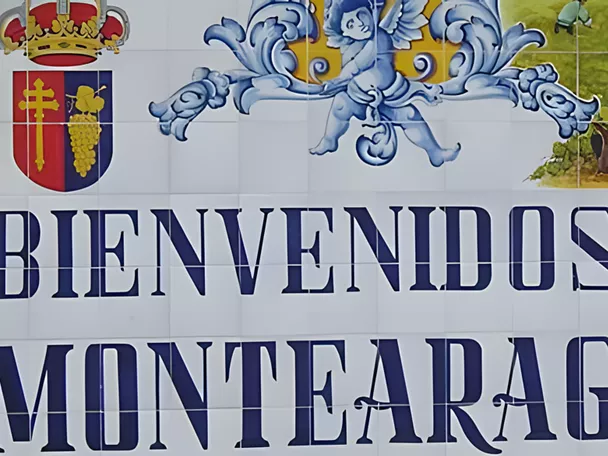 Panel cerámico de bienvenida con letras azules y escudo decorativo