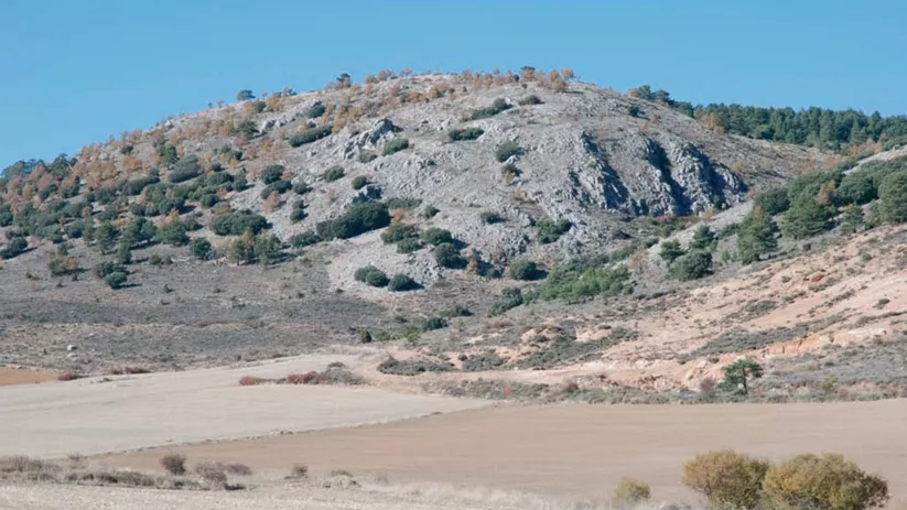 Cerro rocoso junto a campos agrícolas