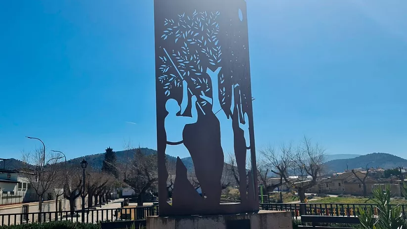 Escultura metálica con figuras humanas y ramas recortadas