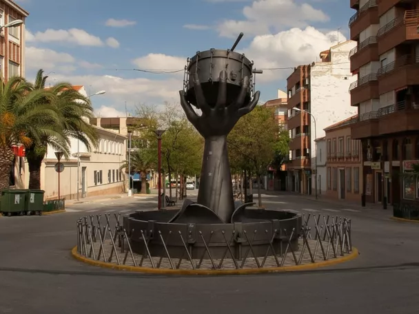 Rotonda central con la escultura del tambor, flanqueada por calles y fachadas urbanas.