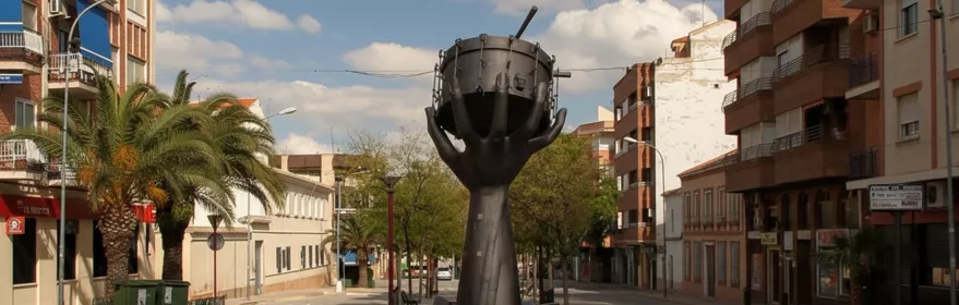 Rotonda central con la escultura del tambor, flanqueada por calles y fachadas urbanas.