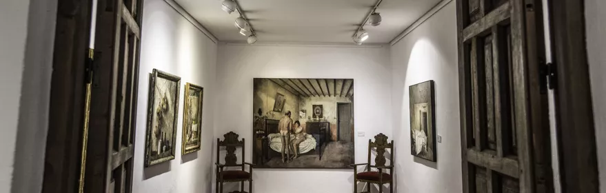 Sala de exposición con cuadros y mobiliario histórico iluminado