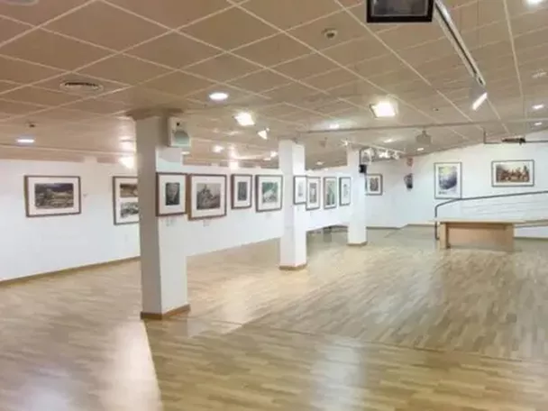 Sala amplia de exposiciones con suelo de madera y cuadros enmarcados.