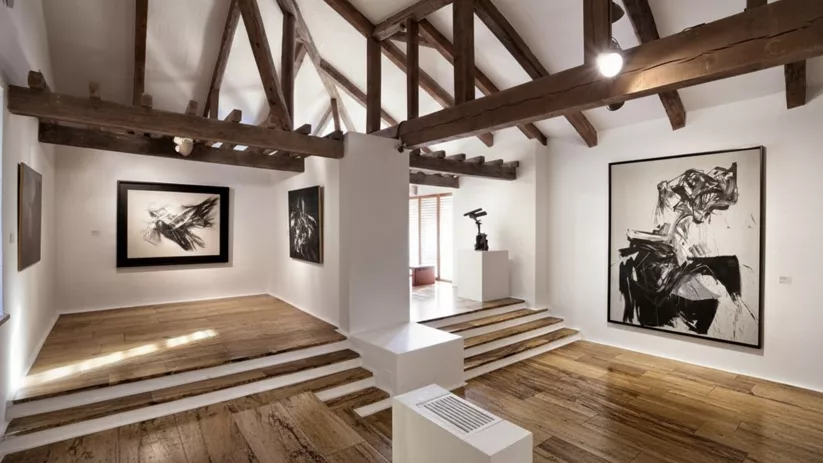 Galería con vigas de madera y arte abstracto