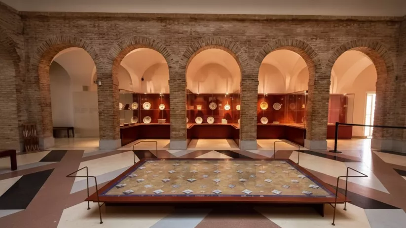 Sala con arcos de ladrillo y vitrinas, con un mosaico en el suelo en el centro.