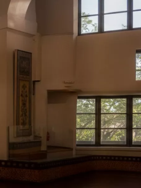 Gran sala iluminada con paneles de azulejos y ventanales, vista panorámica del museo.