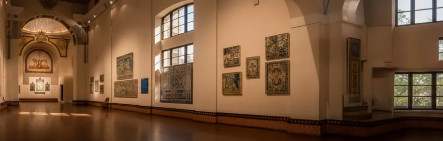 Gran sala iluminada con paneles de azulejos y ventanales, vista panorámica del museo.