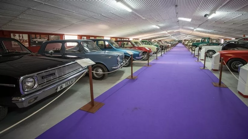 Colección de coches clásicos en un largo pasillo interior.