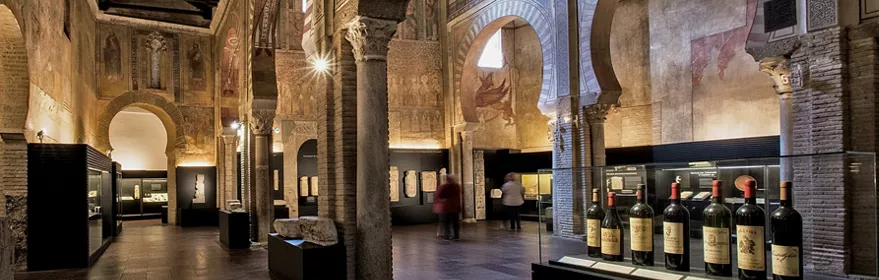 Sala expositiva con piezas arqueológicas y frescos en las paredes.