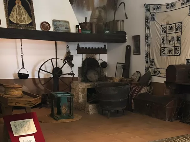 Sala museística con utensilios tradicionales, rueca y objetos religiosos.