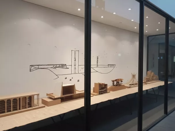 Vitrina con maquetas arquitectónicas en sala blanca.
