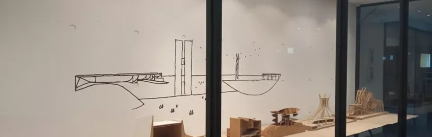 Vitrina con maquetas arquitectónicas en sala blanca.