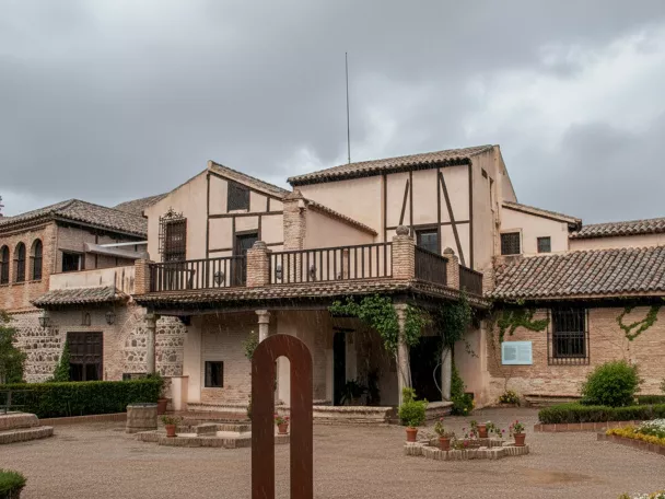 Fachada de edificio tradicional con patio ajardinado en día nublado.