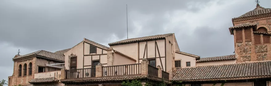 Fachada de edificio tradicional con patio ajardinado en día nublado.