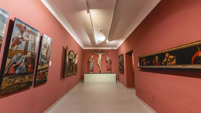 Sala de museo con pinturas y tallas religiosas.