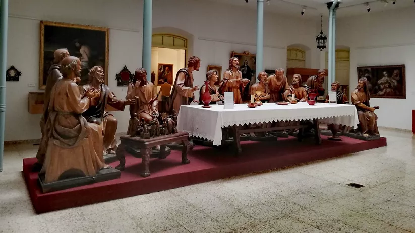 Conjunto escultórico de madera representando una escena religiosa alrededor de una mesa