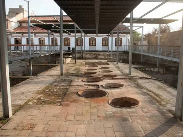 Patio industrial con pasarelas metálicas y varias piletas circulares en el suelo.