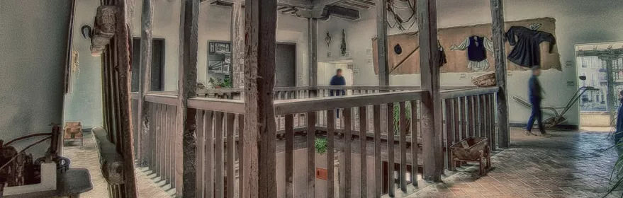 Galería interior de madera con vigas vistas y objetos tradicionales expuestos en las paredes.