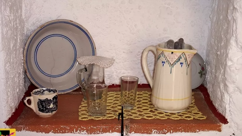 Estantería empotrada con vajilla, jarra y vasos de vidrio.