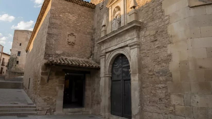 Fachada de piedra con portada clásica y puerta de madera.