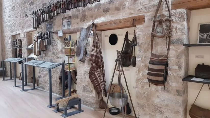 Paneles informativos y utensilios antiguos colgados en pared rústica.