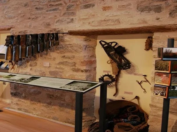 Sala expositiva con herramientas tradicionales sobre muros de piedra.