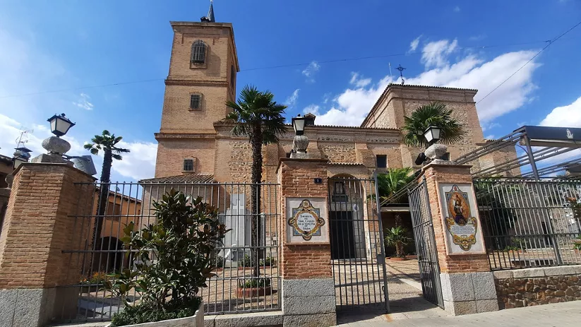 Fachada de iglesia de ladrillo con torre y patio de entrada