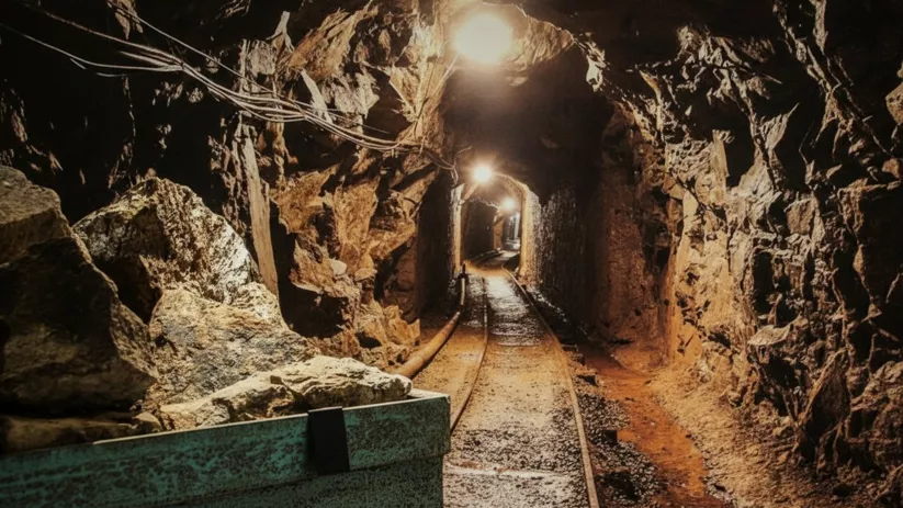 Túnel minero iluminado con vías.