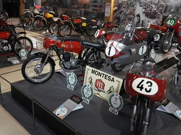 Exposición de motocicletas de competición antiguas en una sala de museo.
