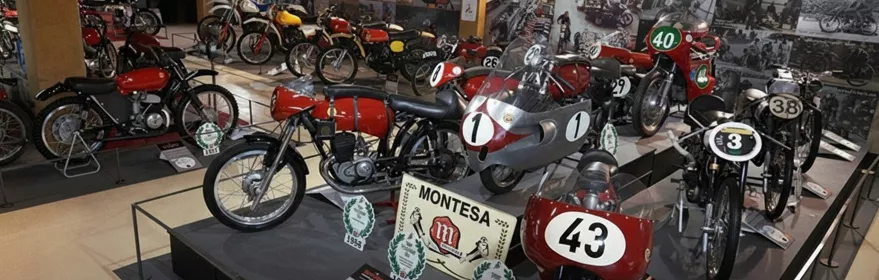 Exposición de motocicletas de competición antiguas en una sala de museo.
