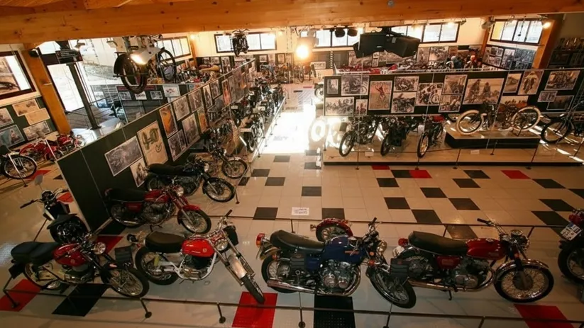 Vista general de museo de motocicletas con vitrinas, paneles y motos clásicas.
