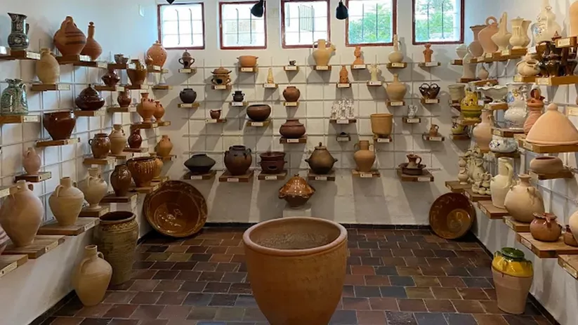Sala amplia con estanterías llenas de piezas de cerámica artesanal y tinajas.