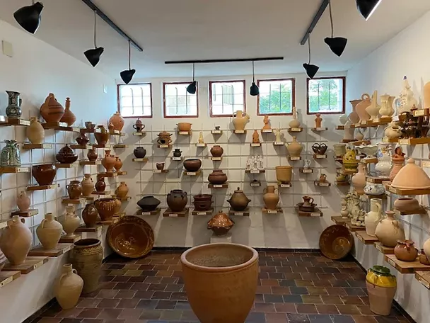 Sala amplia con estanterías llenas de piezas de cerámica artesanal y tinajas.