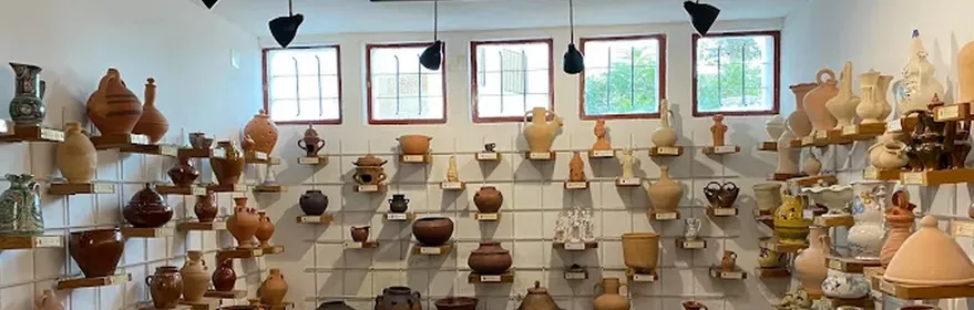 Sala amplia con estanterías llenas de piezas de cerámica artesanal y tinajas.