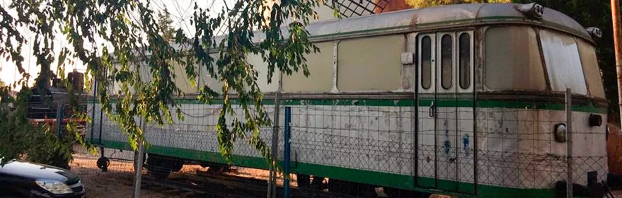 Vagón ferroviario histórico junto a un molino de viento.