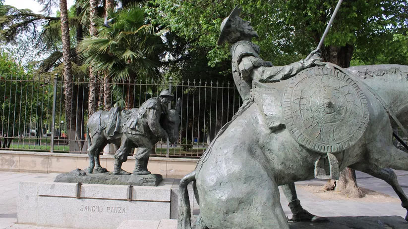 Esculturas de caballero y escudero a caballo en un parque arbolado