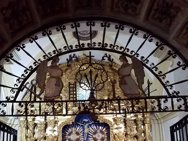 Retablo dorado con rejería y figuras religiosas