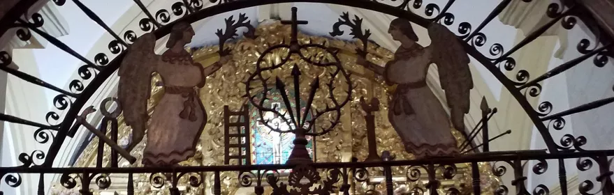 Retablo dorado con rejería y figuras religiosas